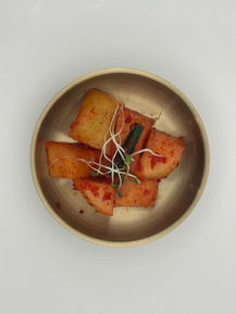 Diced radish kimchi with sprouts in a metal bowl