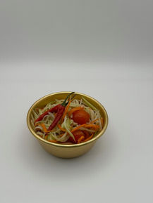 Thai papaya salad with chilies, tomatoes in a golden bowl