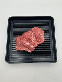 Thin slices of raw beef on a black tray