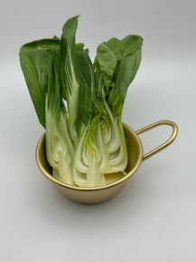 Fresh bok choy in a gold cup, some pieces split